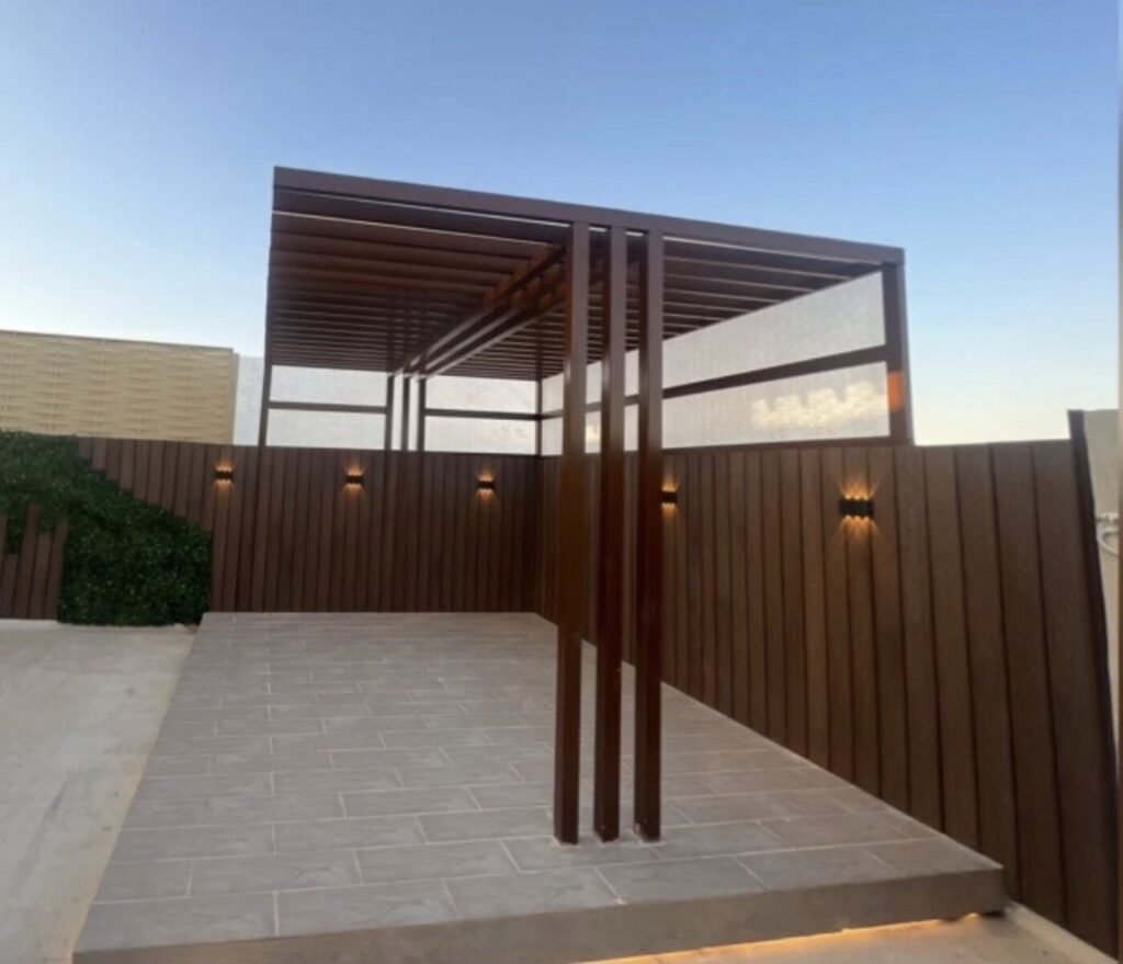 جلسة خارجية مبنية مع برجولا وتكسيات خشبية وإضاءة مخفية وعشب صناعي